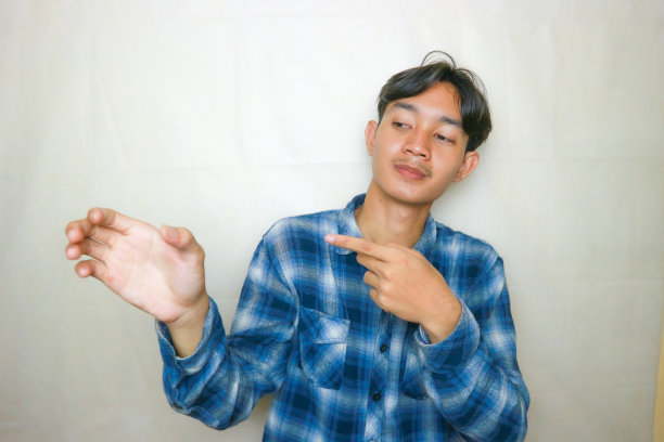 一名印尼亚裔男子身穿蓝色衣服，以白色为背景，正在拍摄各种表情的照片图片下载