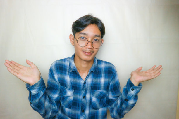 一名印尼亚裔男子身穿蓝色衣服，以白色为背景，正在拍摄各种表情的照片图片下载