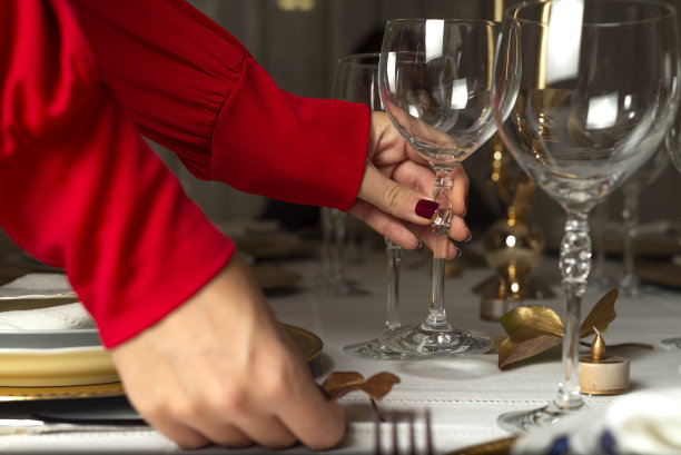 面目全非的女人在组织优雅的圣诞大餐。女性的手在家里为圣诞大餐摆桌子的特写照片。图片下载