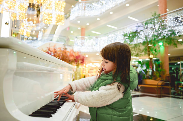 圣诞节期间，一个小女孩在商场里弹钢琴。图片下载