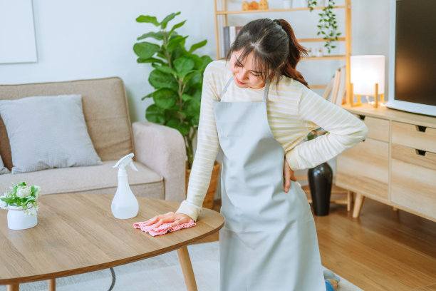 一位亚洲妇女在家里的客厅里做春季大扫除时头痛不已图片下载