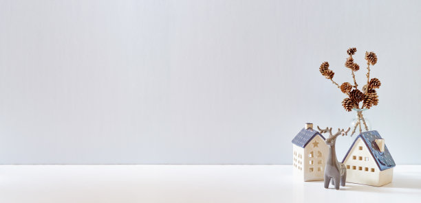 圣诞节，新年居家装饰。空的白色墙壁上装饰着圣诞小房子和白色桌子上的鹿。模拟展示作品图片下载