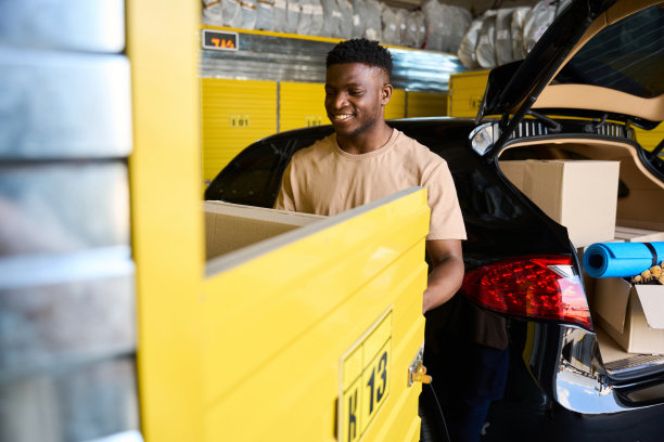 一个年轻人把一个装着东西的纸板箱装进黄色牢房图片下载