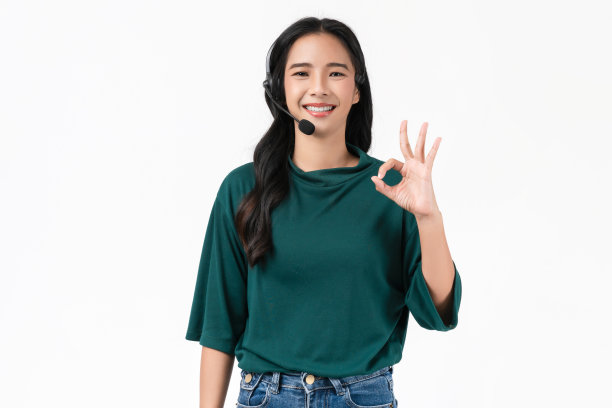 开朗美丽的亚洲女性顾问在工作场所戴着白色背景的客户支持电话接线员的麦克风耳机。图片下载