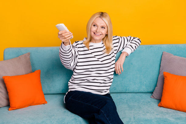 照片中的老人女士改变温度公寓使用遥控空调隔离明亮的色彩背景图片下载