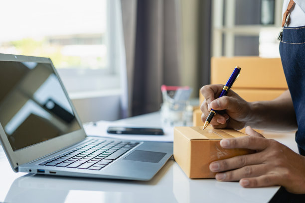小型创业企业中小企业主使用智能手机或平板电脑接收和监控在线订单，以准备产品箱交付。特写照片图片下载