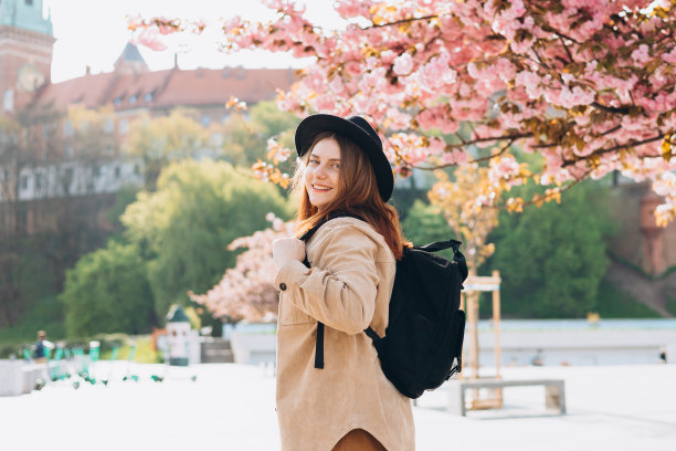 迷人的年轻女游客正在探索新的城市。30多岁的红发女孩戴着黑帽子在波兰克拉科夫瓦维尔城堡附近休息。春天去欧洲旅行。高质量照片图片下载