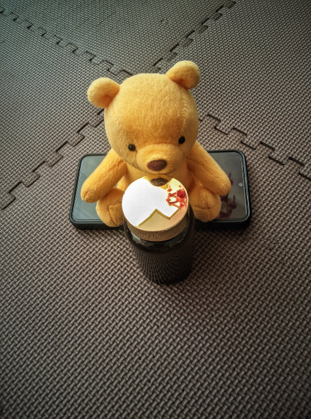 一只泰迪熊坐在手机上。玩具泰迪熊的美丽图片。图片下载