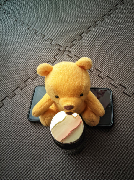 一只泰迪熊坐在手机上。玩具泰迪熊的美丽图片。图片下载