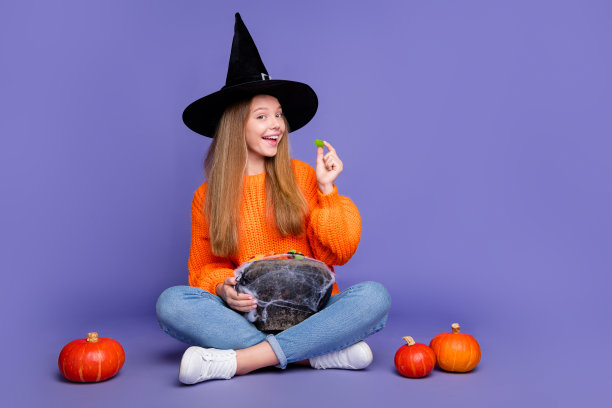 完整的照片美味的糖果果酱年轻的女孩巫婆拿满桶糖果得到万圣节孤立的紫罗兰色背景图片下载