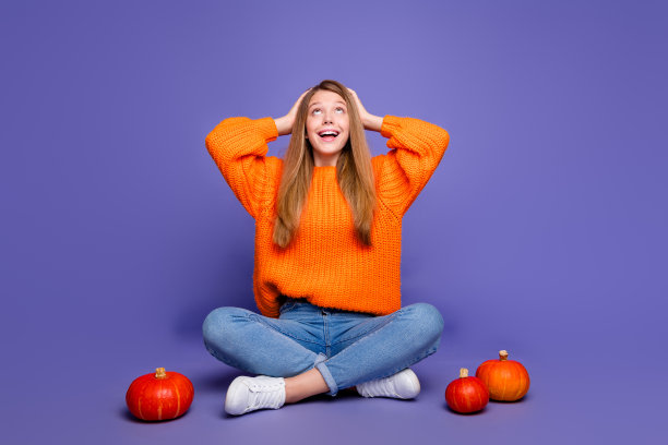 女孩双手放在头上的全身照片看起来很惊讶，在紫色的背景下，大型万圣节音乐会的空旷空间被隔离在南瓜附近图片下载