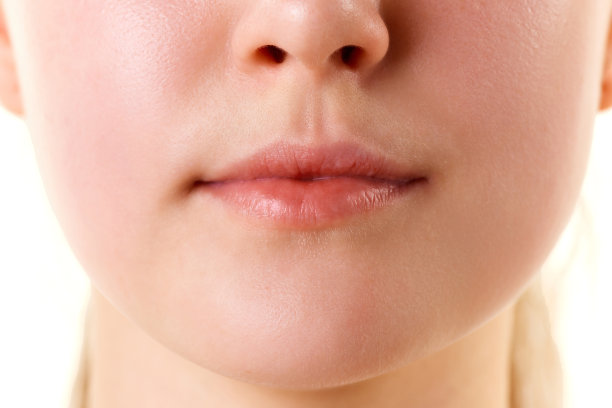 近距离剪裁的照片，嘴唇没有口红。嘴巴闭着。自然光泽的嘴唇和女人的皮肤。增加唇部美容。图片下载