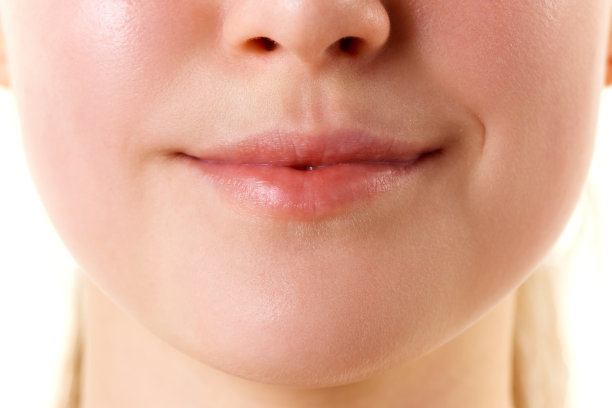近距离剪裁照片的女性脸，嘴唇没有口红。微笑的嘴。自然光泽的嘴唇和女人的皮肤。增加唇部美容。图片下载