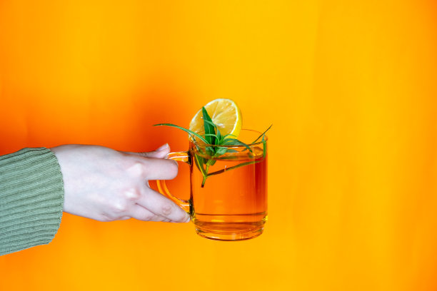 手持橙色背景的玻璃杯图片下载