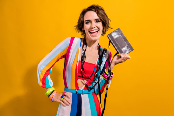 积极开朗的女孩拿着录像带在晚会上看电影的照片，孤立的明亮的色彩背景图片下载