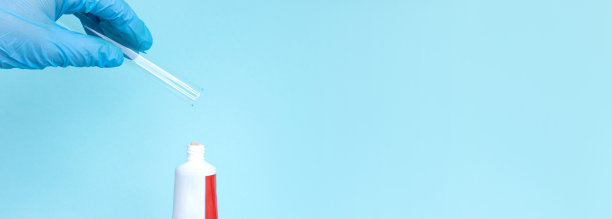 牙科概念照片。医生戴着蓝色手套，在牙膏管下面拿着装有钙的玻璃管。图片下载