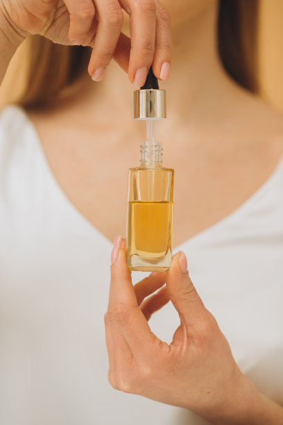 皮肤护理。美女肖像的妇女手持滴管瓶孤立的米色背景。特写照片。图片下载