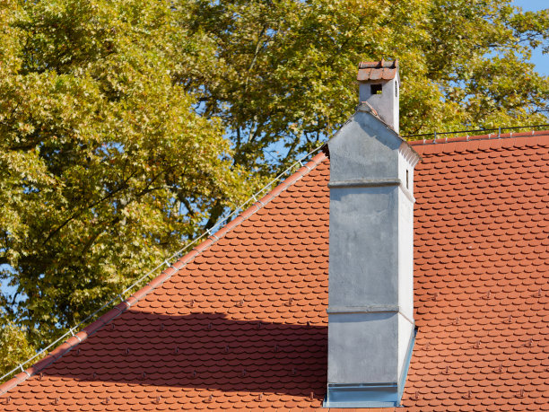 屋顶上的混凝土烟囱的特写照片，红色的瓷砖，背景是一棵树图片下载