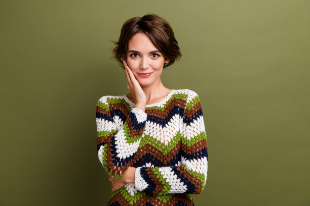 可爱的年轻女士的照片肖像触摸脸颊护肤可爱穿时髦的印花针织品服装孤立的卡其色背景图片下载