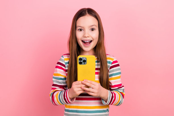 小学生收到她的第一个苹果智能手机的照片，昂贵的设备，粉红色背景的惊喜图片下载