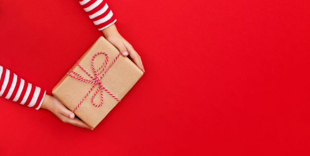 圣诞彩旗礼盒在孩子们的手中以红色为背景，赠送礼物图片下载