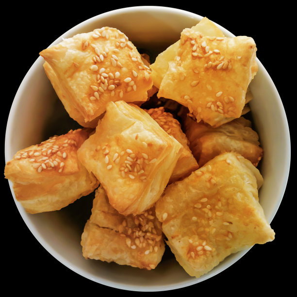一束新鲜出炉的小方形芝麻酥皮祖祖在一个白色的陶瓷碗孤立的黑色背景高分辨率股票照片图片下载