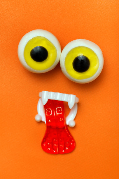 万圣节糖果:橙色的糖果脸，粘着眼睛、牙齿和舌头图片下载