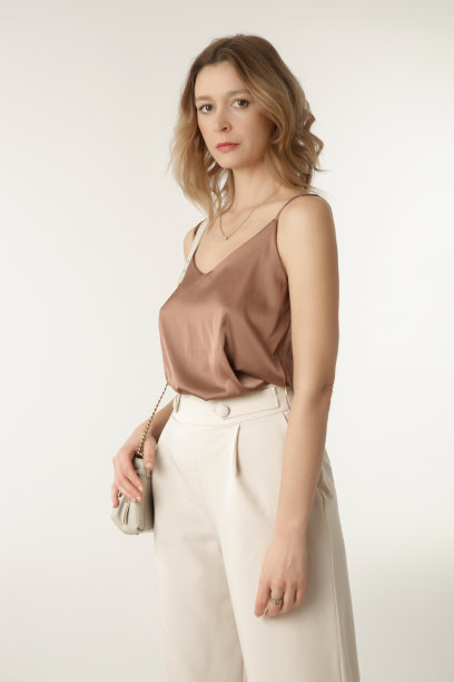一系列的工作室照片的年轻女模特穿着简单美丽的服装，丝绸缎衬衫和白色阔腿裤图片下载