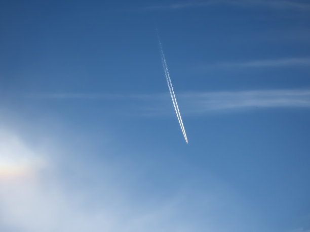 飞机在蓝天中飞行，有白云和尾迹。图片下载