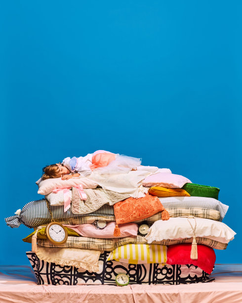 晚安，各位。小公主的肖像，在蓝色的工作室背景上，在一大堆枕头上熟睡。图片下载