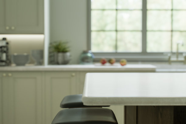 厨房内部有一个带有白色石材台面的岛台，用于放置和广告产品，与窗边厨房的模糊背景相对。三维渲染图片下载