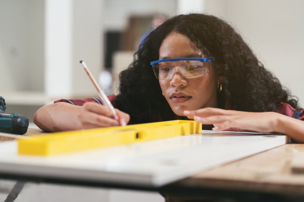 女木匠在木工车间使用水位计或水平仪进行设计工作。在家具车间工作的女细木工图片下载