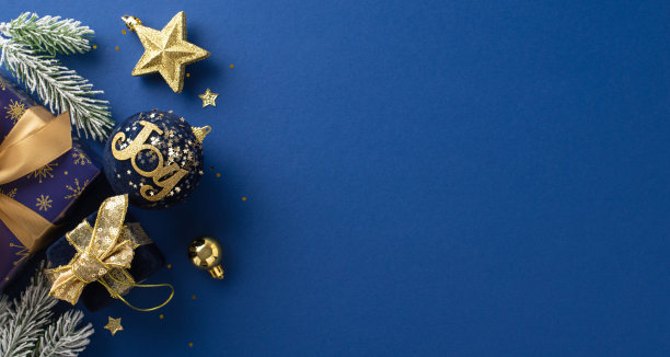 闪闪发光的圣诞魔法概念。顶视图图片闪闪发光的蓝色和金色包裹的礼物，明星玩具，明亮的五彩纸屑，冷杉树枝与霜在优雅的蓝色表面，可为您的文字或广告图片下载