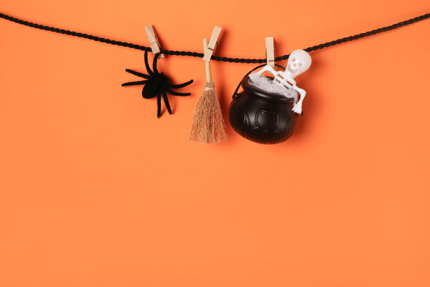 创意万圣节卡片与女巫集蜘蛛，扫帚和骨架上的绳子，橙色的背景。本空间图片下载