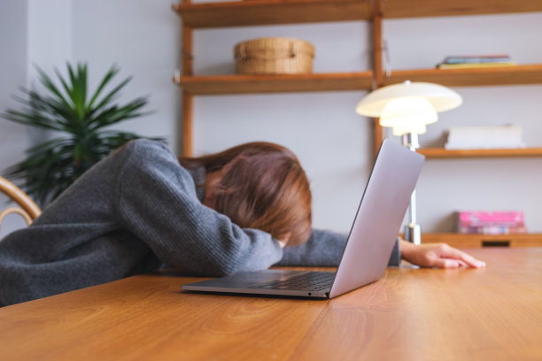 一个女人在笔记本电脑上工作时累了，在桌子上睡着了图片下载