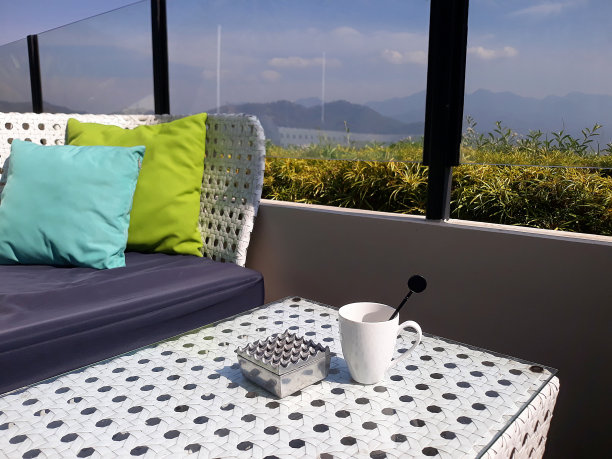 在丘陵地区的咖啡馆里，桌子、椅子、沙发、烟灰缸里的香烟和一杯咖啡茶。白天的山景图片下载