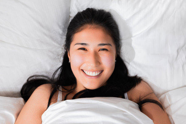 照片肖像高兴地笑着洁白的牙齿哈萨克斯坦日本中国女孩在床上醒来躺在床上在周末微笑休息后辛苦的一周图片下载