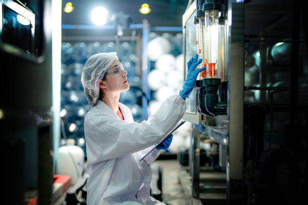 工业工厂的科技工人在检查反渗透机系统的质量。女工在控制面板上记录数据，测量便携式回收装置的压力。图片下载