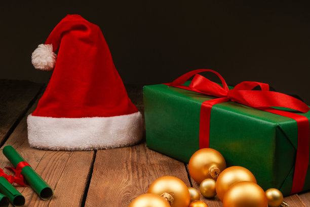 圣诞Flatlay礼盒和圣诞树装饰品的俯视图照片。木制背景上的圣诞老人帽子。圣诞背景与文字的地方。Copyspace。圣诞树玩具。图片下载