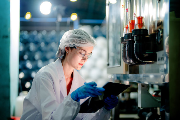 工业工厂的科技工人在检查反渗透机系统的质量。女工在控制面板上记录数据，测量便携式回收装置的压力。图片下载