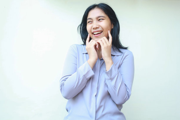 激动的美女亚洲年轻的女商人用幸福的微笑摸着脸颊，望向一旁的空地，表达女性的喜悦和满足，穿着正装，孤立在白色的背景中图片下载