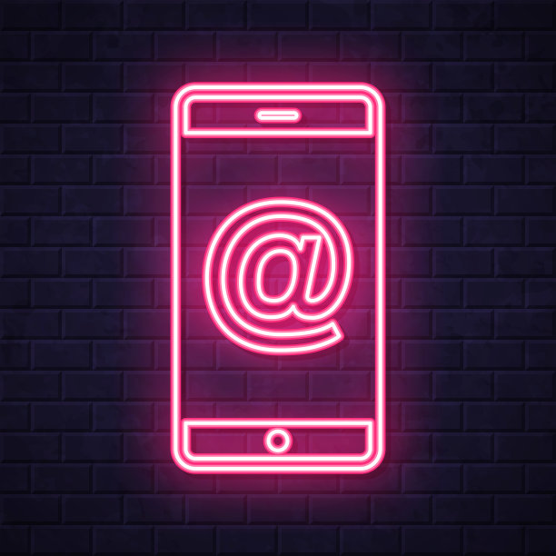带有At符号的智能手机。在砖墙背景上发光的霓虹灯图标图片下载