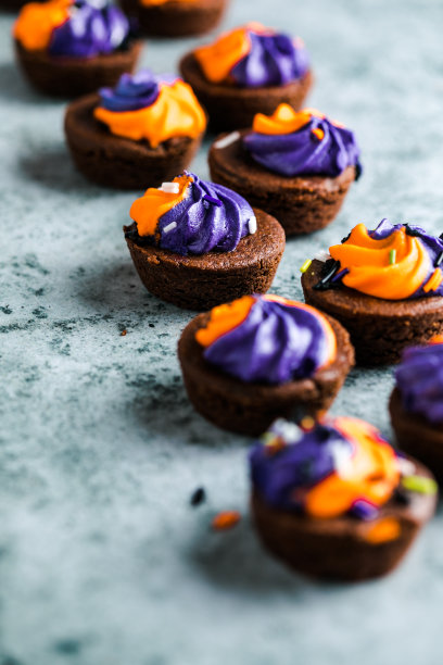 幽灵奶油装饰的布朗尼纸杯蛋糕，在灰色背景的石板上洒上糖屑。万圣节快乐的概念。美国文化和传统图片下载