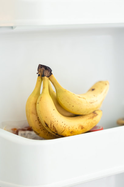 香蕉在打开的冰箱容器的架子上的特写。图片下载