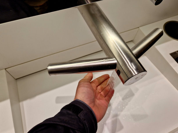 时尚的洗涤角。不锈钢皂液机和纸巾机。白色可丽耐家具水槽，洗脸盆，杠杆水龙头。柜台上的废纸篓，男人手里，握着手掌图片下载