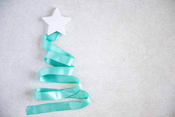 圣诞树由蓝色绿松石丝带与白色星星在灰色的石头背景。带有复制空间的抽象照片。新年或圣诞节庆祝概念图片下载