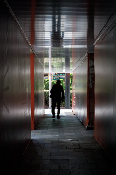 一个男人走在建筑墙的走廊里图片下载