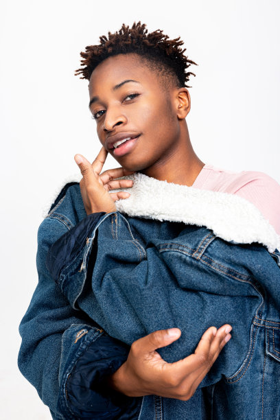 照片英俊年轻的非洲模特看着镜头微笑穿着时尚时尚的衣服牛仔外套和粉红色的普通t恤图片下载