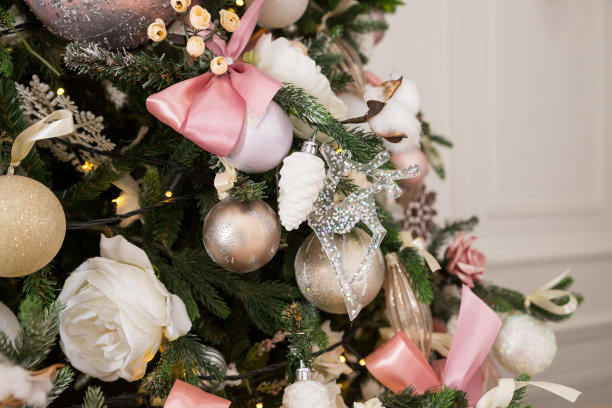 花环、金箔、粉色和白色的圣诞装饰球挂在装饰圣诞树上。概念新年庆祝背景。图片下载