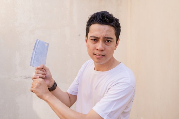 印尼男人准备摆姿势的时候，手里拿着屠刀，穿着白色的t恤。图片下载